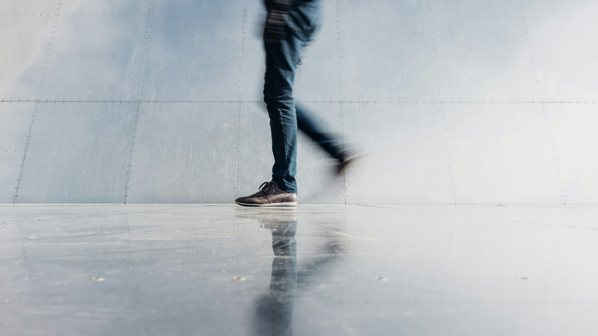 Dark indigo jeans walking past a grey wall