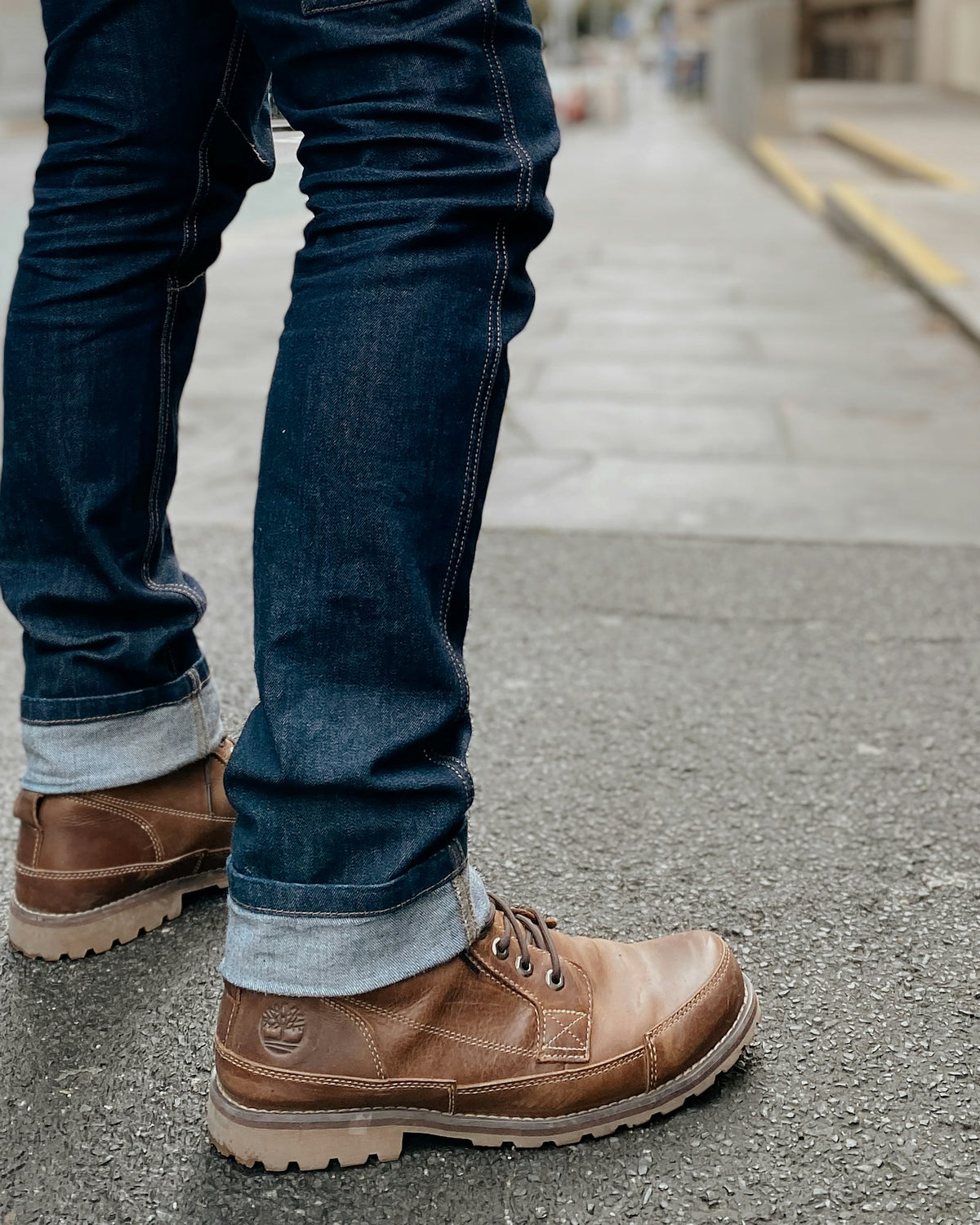 Raw indigo jeans worn with brown boots, cuffed once at the hem